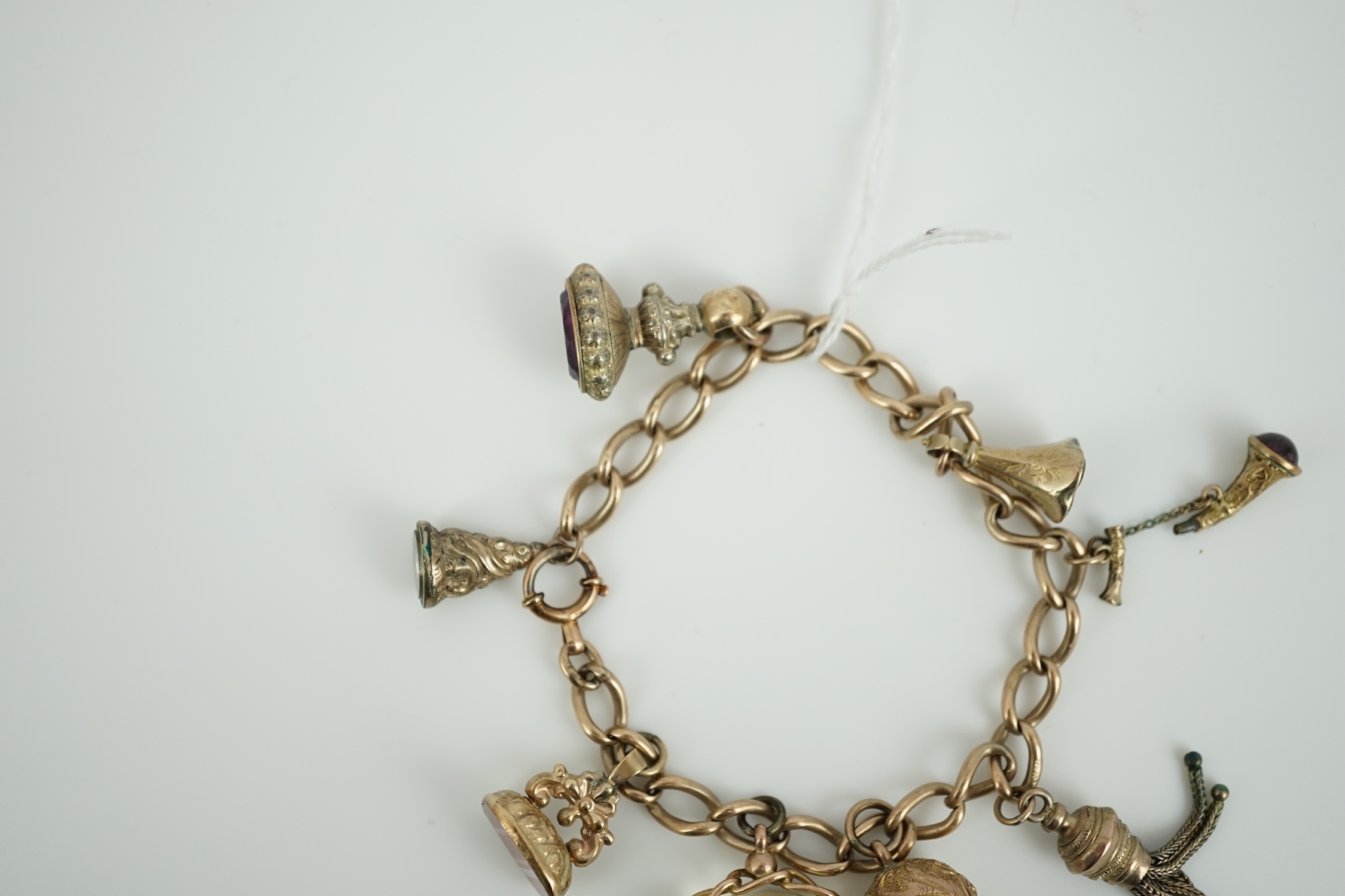 A 9ct gold charm bracelet, hung with eight assorted yellow metal overlaid charms, gross weight 33.4 grams.